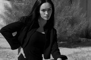 A woman wearing a black midi dress with criss cross back strap detail. 