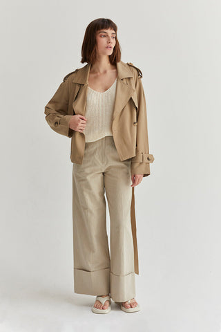 a model in beige pants and a brown trench-style jacket