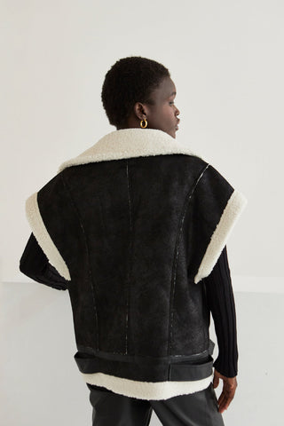 a model in a black vest with sherpa