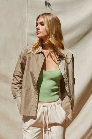 a model in a green tank and beige shirt