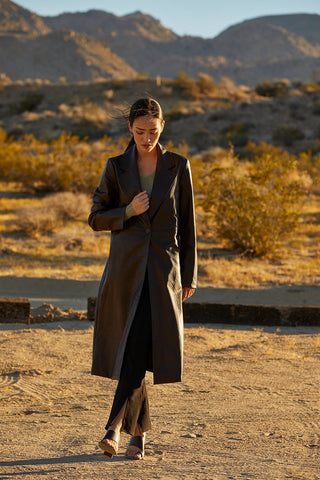 a model walking outdoors in a leather coat