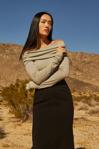 A woman wearing a fold-over off shoulder knit cropped top with side ruched.