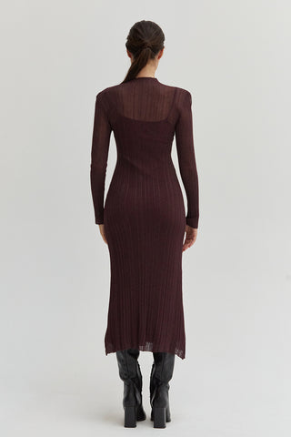 A woman wearing a sheer lurex knit mock neck maxi dress with long sleeves. 