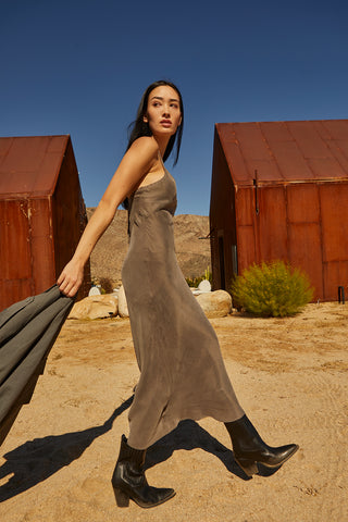 A woman wearing a cupro maxi slip dess in charcoal.