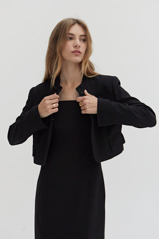 A woman wearing a tencel wool blend cropped blazer with two hidden button front closure.