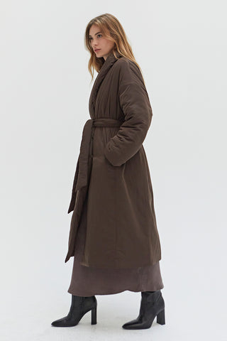 A woman wearing an oversized brown duvet puff coat with invisible side pockets and detachable self belt. 