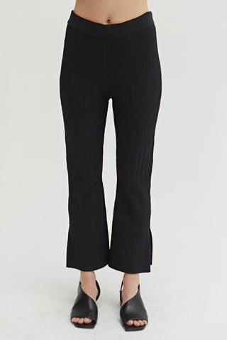 A woman wearing a black cropped stripe textured pattern knit pants.