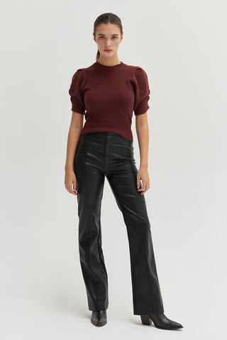 A woman wearing black vegan leather pants with straight leg silhouette. 