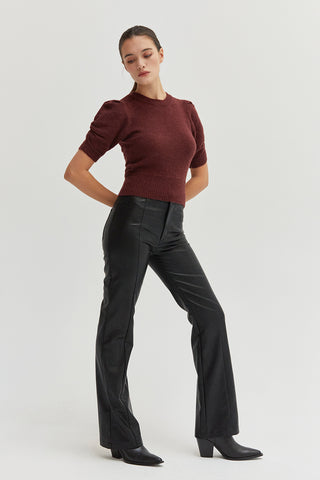 A woman wearing black vegan leather pants with straight leg silhouette. 