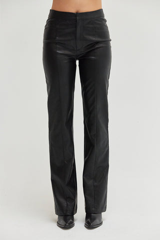 A woman wearing black vegan leather pants with straight leg silhouette. 