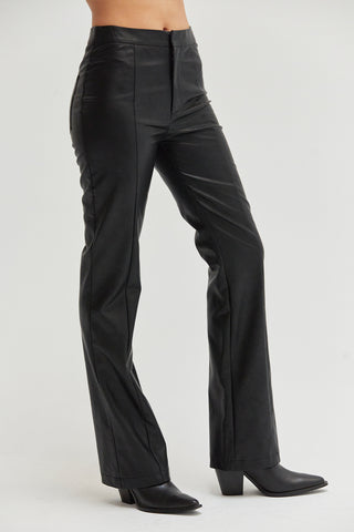 A woman wearing black vegan leather pants with straight leg silhouette. 