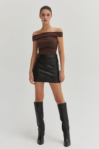 A woman wearing a black vegan leather mini skirt.