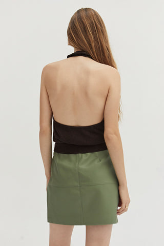 A woman wearing a green vegan leather mini skirt.