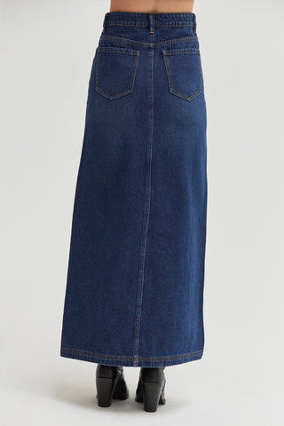 A woman wearing a high waisted denim maxi skirt with front center slit. 