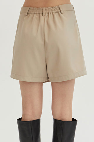 A woman wearing a bone mini skort with elasticized back waistband.