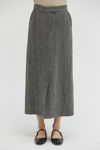 A woman wearing a high waisted midi length skirt with a herringbone pattern.  