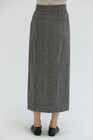 A woman wearing a high waisted midi length skirt with a herringbone pattern.  