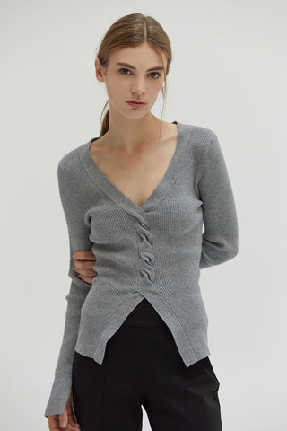 A woman wearing a front twist sweater top with slit detail on sleeves.