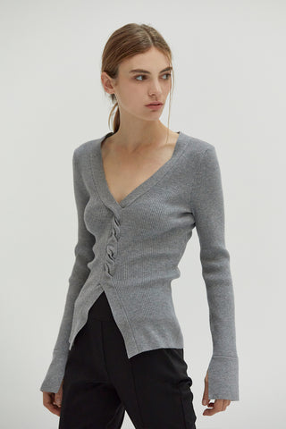 A woman wearing a front twist sweater top with slit detail on sleeves.