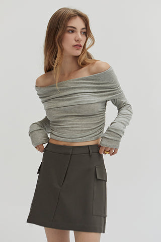 A woman wearing a fold-over off shoulder knit cropped top with side ruched.