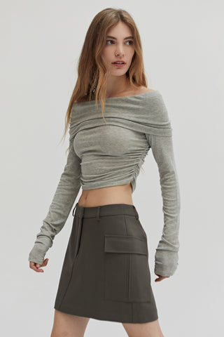 A woman wearing a fold-over off shoulder knit cropped top with side ruched.