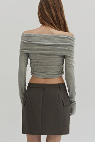 A woman wearing a fold-over off shoulder knit cropped top with side ruched.