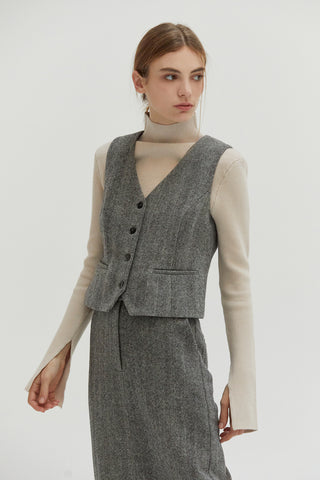 A woman wearing a form fitting vest made from wool material. 