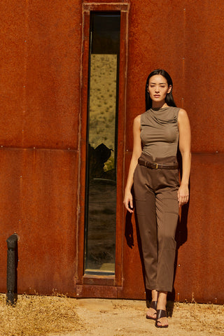 A woman wearing a high cowl neck sleeveless knit top.