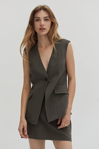 A woman wearing a dark olive suit vest.