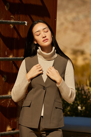 A woman wearing a turtleneck top with exaggerated side slits. 