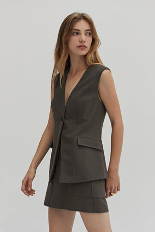 A woman wearing a dark olive suit vest.