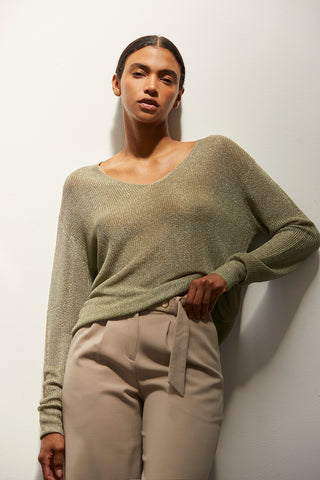 A woman wearing a green shimmer sweater knit top.