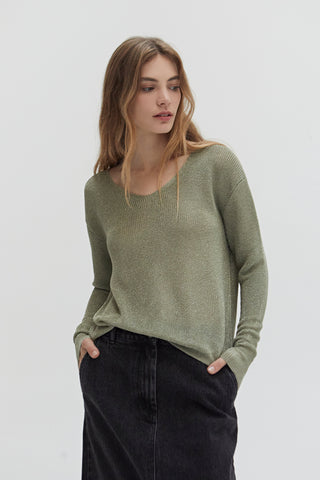 A woman wearing a green shimmer sweater knit top.