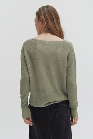 A woman wearing a green shimmer sweater knit top.