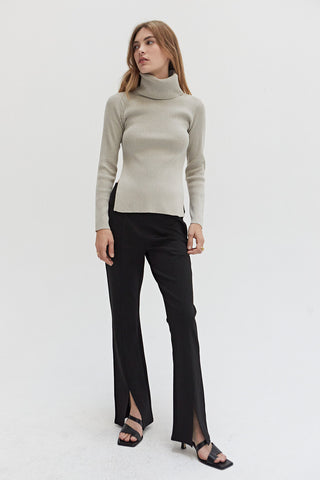 A woman wearing a turtleneck top with exaggerated side slits. 