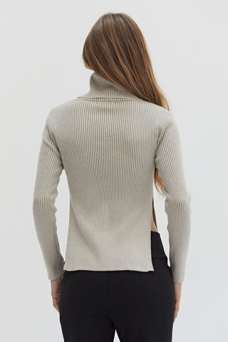 A woman wearing a turtleneck top with exaggerated side slits. 