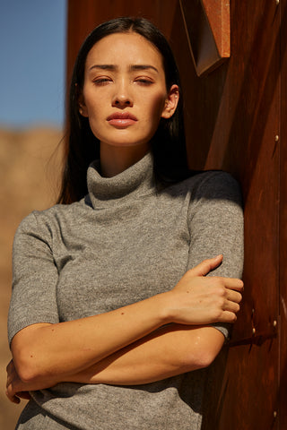 A woman wearing a grey turtleneck top. 