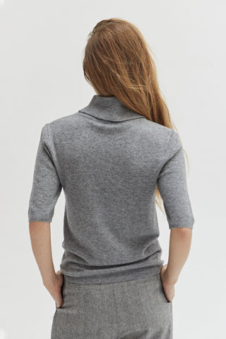 A woman wearing a grey turtleneck top. 