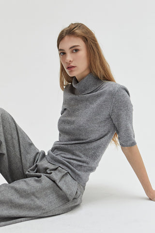 A woman wearing a grey turtleneck top. 