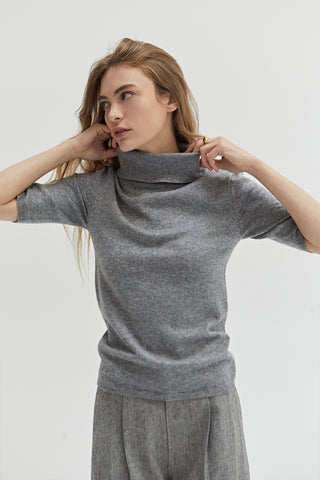 A woman wearing a grey turtleneck top. 