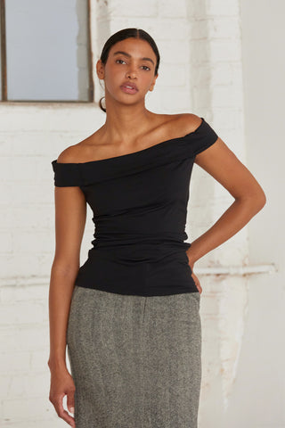 A woman wearing an off shoulder top with ruching at the sides. 