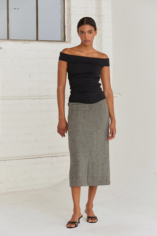 A woman wearing a high waisted midi length skirt with a herringbone pattern.  