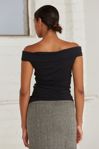 A woman wearing an off shoulder top with ruching at the sides. 