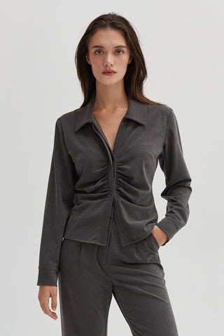 A woman wearing a ruched button up top. 