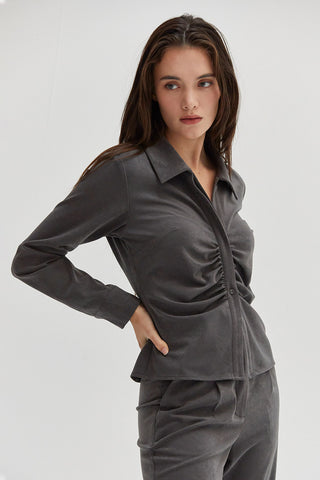 A woman wearing a ruched button up top. 