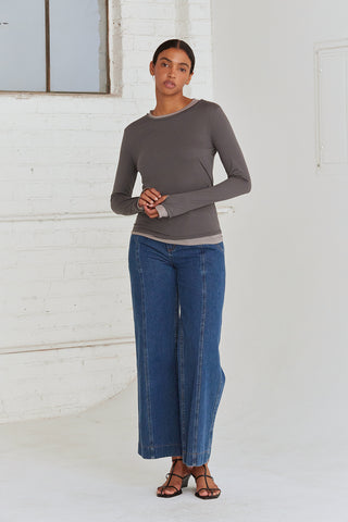 A woman wearing a dual layered long sleeve top with thumbholes. 