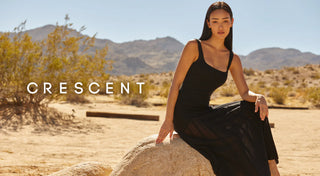 a woman sitting on a rock in a black dress